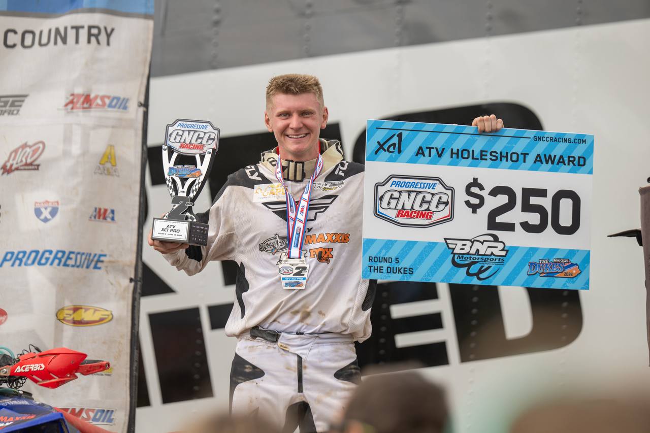 Rider holding GNCC ATV holeshot trophy and award sign